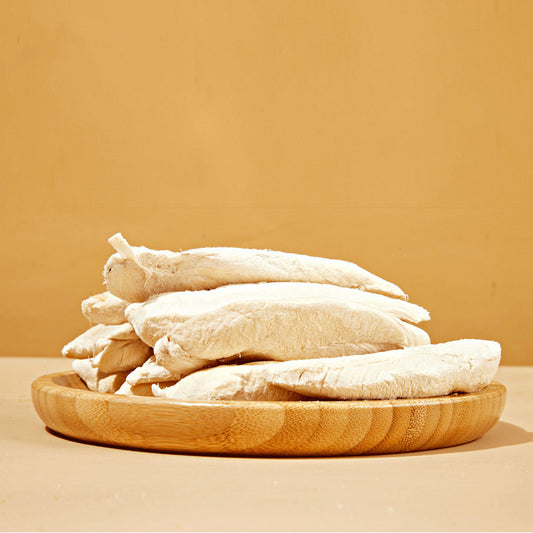 A wooden plate full of Freeze-Dried Chicken Breast tenders from Arya! Sit. Side view of tenders stacked high. 4"-5" long tenders are whole, not in pieces.
