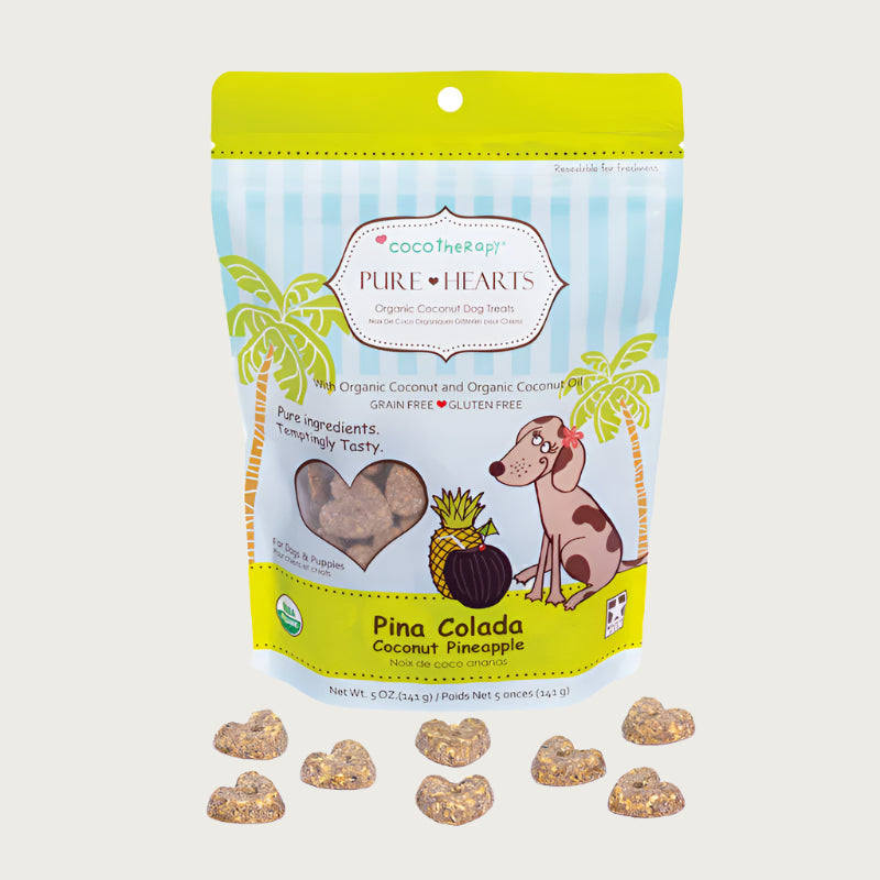 5 oz blue and lime green bag of CocoTherapy Pure Hearts Pina Colada organic coconut dog treats. Made with coconut & coconut oil. Grain-free, gluten free. USDA organic, made in USA. Sample of treats in front of bag are brown, heart-shaped, and nickel sized.