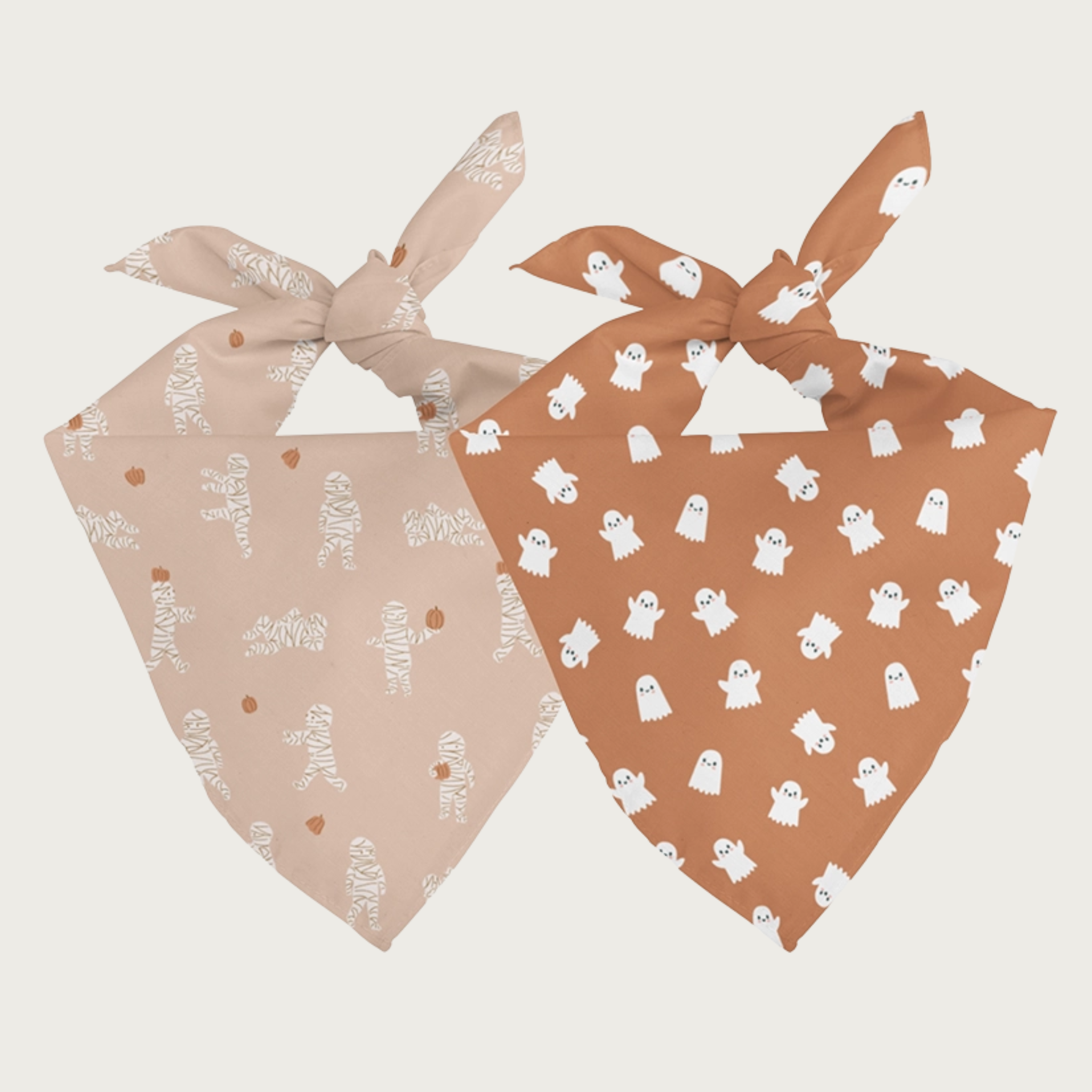 Two sides of the same dog bandana, shown side by side. One side has a pinkish-cream background with simple mummies in different actions. The other side has a light burnt orange background with simple white ghosts in different actions.
