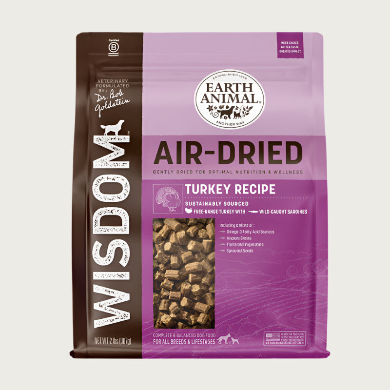 A purple and brown bag of Wisdom Air-Dried Turkey Recipe dog food. Complete & balanced for all breeds & lifestages. Small transparent window shows actual dog food inside (small, rectangular brown bites).