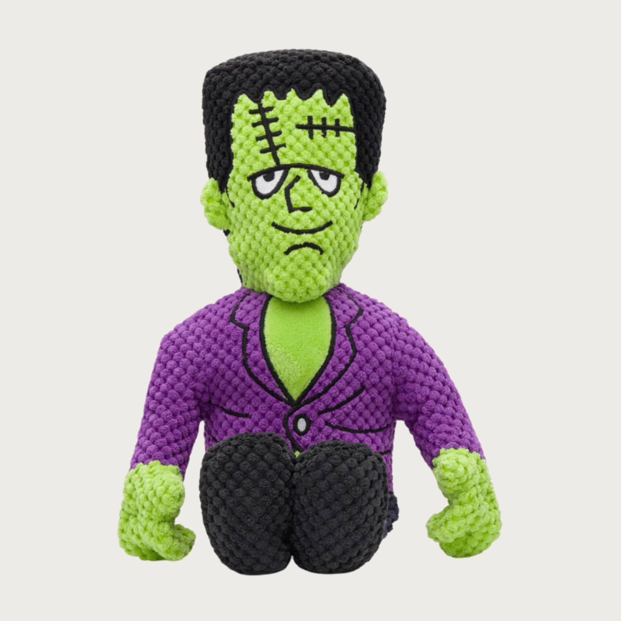Plush Frankenstein dog toy with green face and hands, wearing a purple suit. Facial features are embroidered, and include stitch details and a neutral expression.