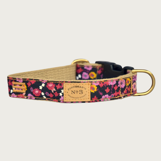 Dog collar with a red & pink floral pattern on a black background, with a brass D-ring and black plastic buckle.