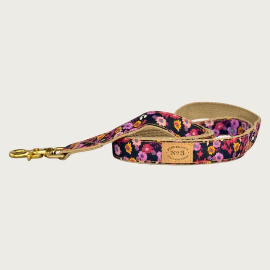 Dog leash with a red & pink floral pattern on a black background, with a brass claw-style clip.