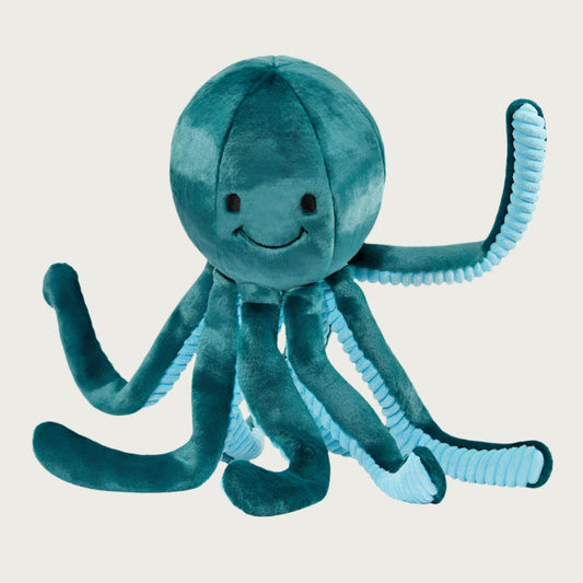 Plush Stevie Octopus dog toy from Fluff & Tuff. Its body is dark teal colored, with the underside of its legs a light teal with ribbed texture. It has a cute smiley face (eyes & mouth) embroidered in black on its head.