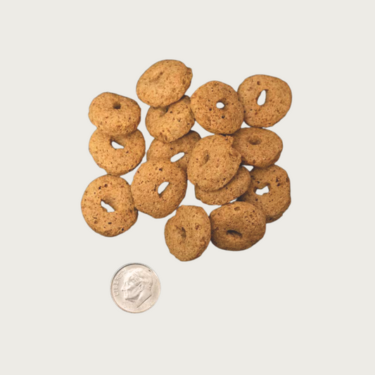 A handful of brown, ring shaped Fromm Crunchy O's dog treats placed next to a dime, for size comparison. One treat is just slightly larger than the dime.