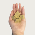 Load image into Gallery viewer, Hand holding small square peanut & banana Goat Milk Biscuit dog treats.