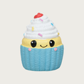 Load image into Gallery viewer, Mini latex cupcake dog toy. It has a light blue base, with strip of pale yellow "cake" above it, with white frosting on top. It has multi-colored sprinkles on the frosting, with a red cherry on top, and sweet, simple, smiley face in black, centered on the front.