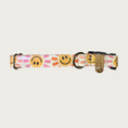 Load image into Gallery viewer, 0.75in width, dog collar with geometric, smiling sunshine face pattern in shades of orange and pink, on a cream background with stainless d-ring and black plastic buckle.