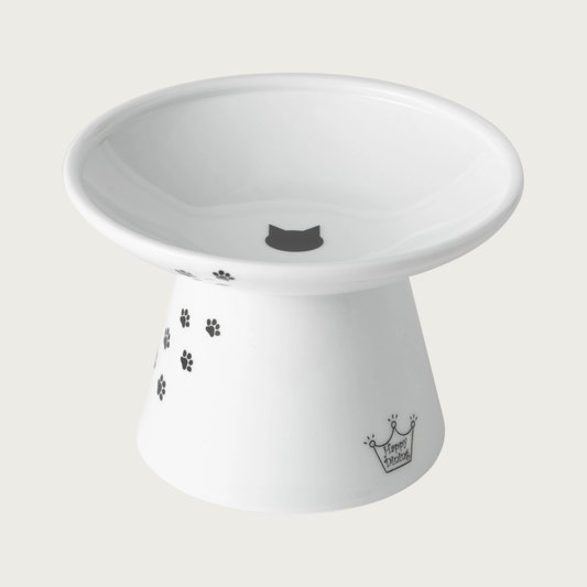 Wide, raised, white porcelain cat food bowl with black paw print design trailing up the side, and a small black cat head silhouette in the center.