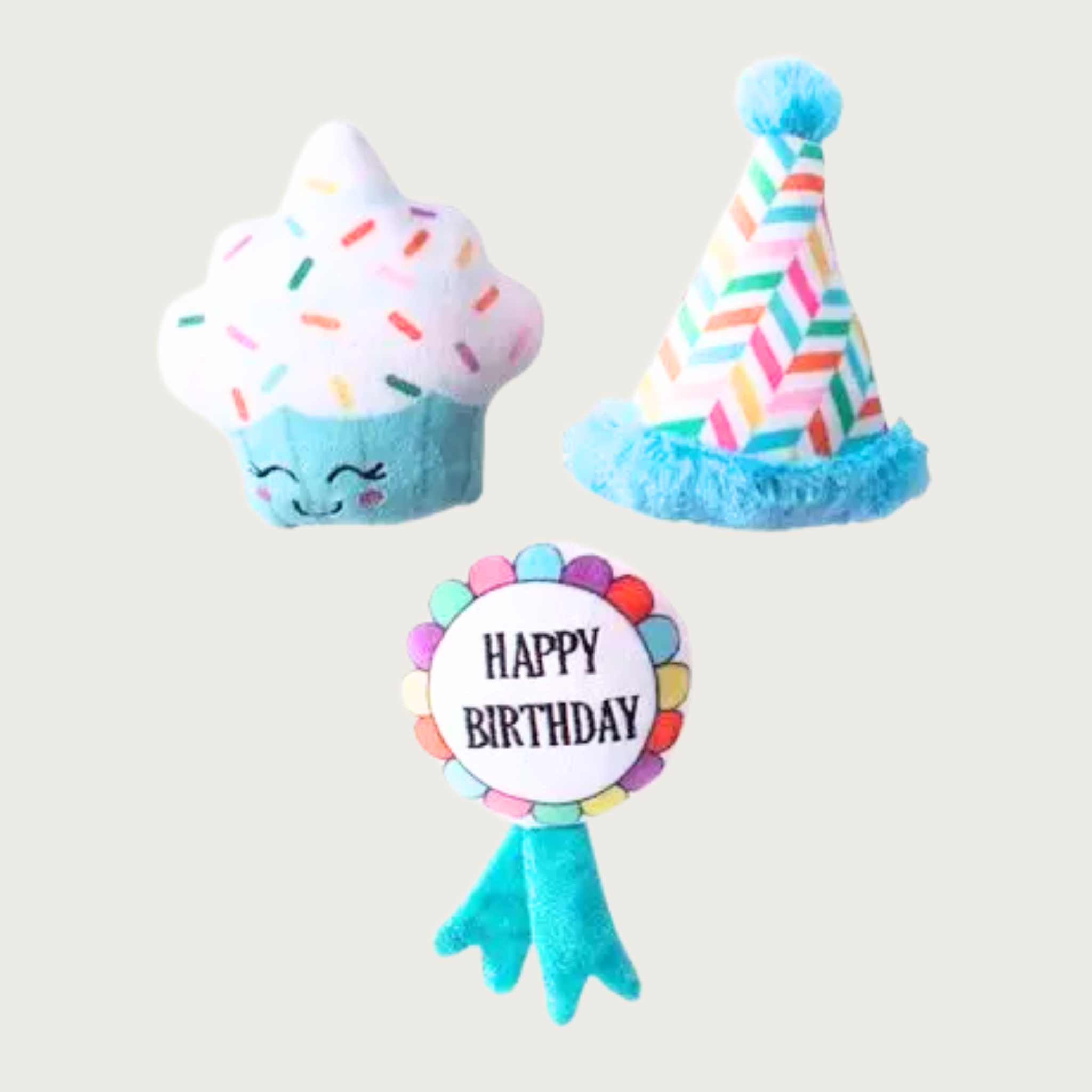 Three mini birthday themed plush dog toys. Cupcake has an aqua blue base with a cute smiley face, with white "frosting" top with multicolored "sprinkles". Birthday Hat has an aqua blue rim & pom pom at the top. Its body features a multicolored chevron design. The Ribbon is shaped like a stereotypical blue ribbon award, with 2 aqua blue tails, and round white body that says "Happy Birthday" in black text, bordered with a multicolored scalloped design edge.