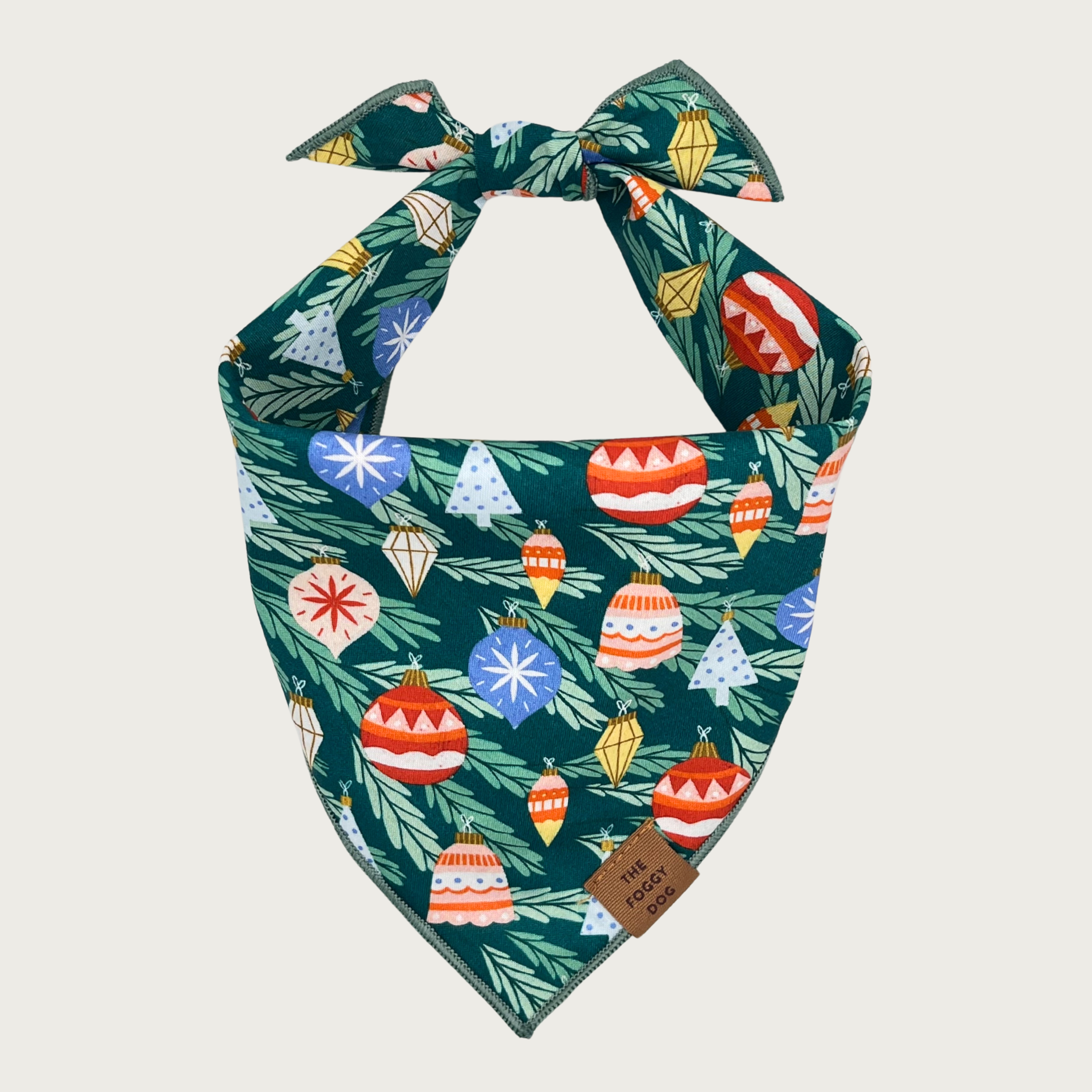 The Foggy Dog Festive Ornaments Christmas-themed dog bandana featuring colorful ornaments in various shapes and sizes on a dark green background with pine needle pattern - perfect for holiday photos and celebrations.