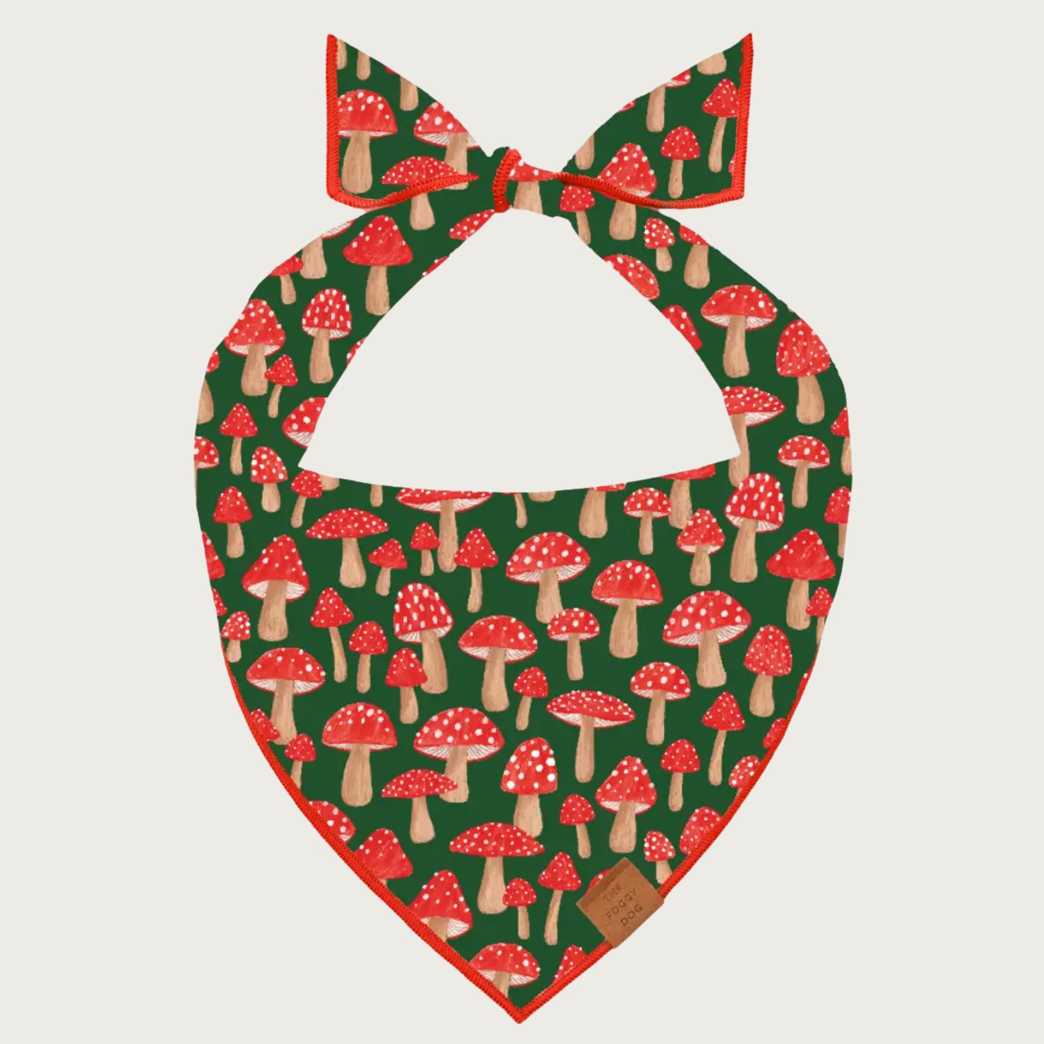 Dog bandana with red mushroom pattern on an olive green background. Mushrooms are varying sizes and have red caps with white dots, and tan stems.