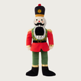 Load image into Gallery viewer, Christmas-themed plush dog toy in the shape of a nutcracker soldier, wearing a red, green, black and gold uniform and hat, with embroidered facial details and wide open mouth.