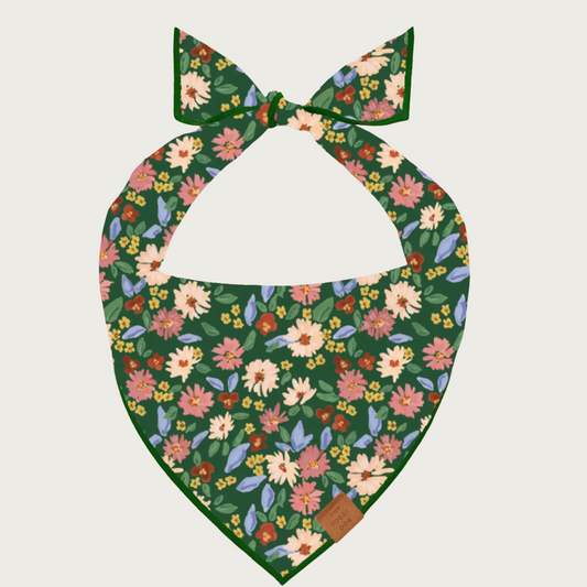 Floral dog bandana featuring flowers in autumnal hues on a dark green background.