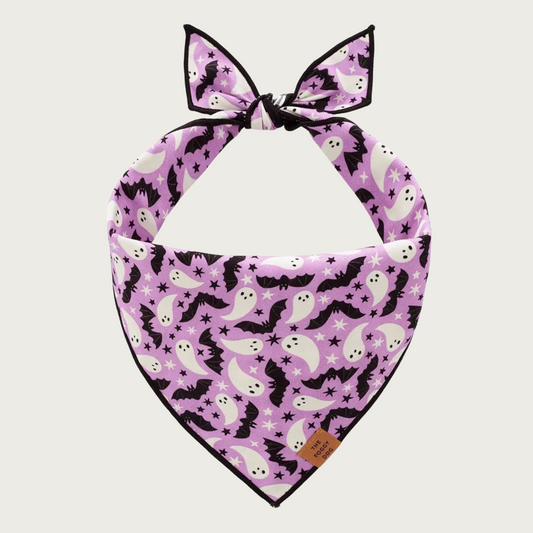 Halloween themed dog bandana, featuring white ghosts and black bats on a lilac colored background.