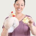 Load image into Gallery viewer, Model holding the plush chicken toy that has been opened up, and has white stuffing exposed. In her other hand, she is holding the smaller chick toy that is inside the chicken.