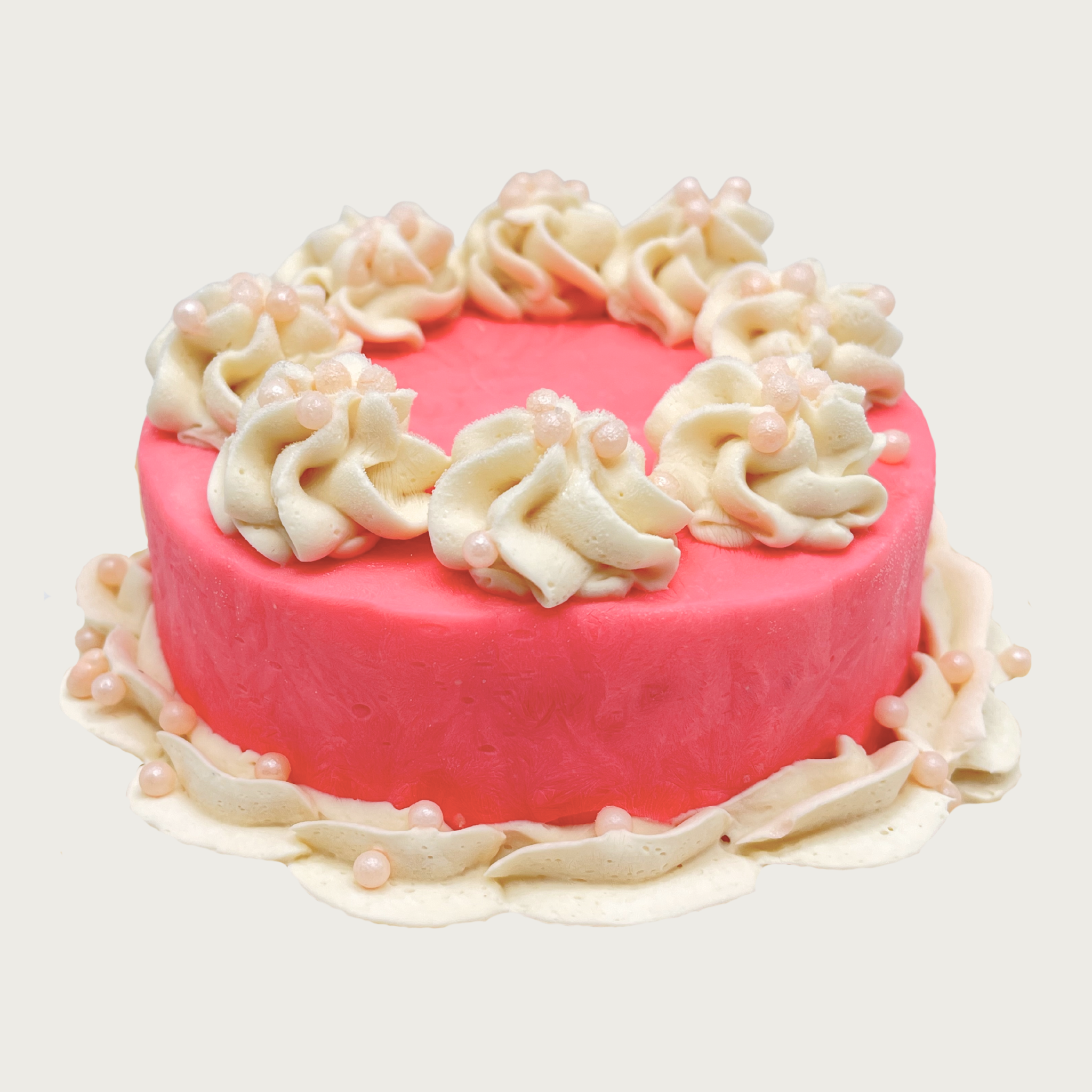 Bright pink iced dog cake with white decorative frosting and pastel pink round non-pareils.