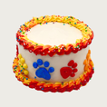 Load image into Gallery viewer, Small birthday cake for dogs. It is covered in cream colored frosting accented with red, orange, and yellow ombre icing on the edges. The sides feature large paw prints in yellow, blue, red and orange icing.