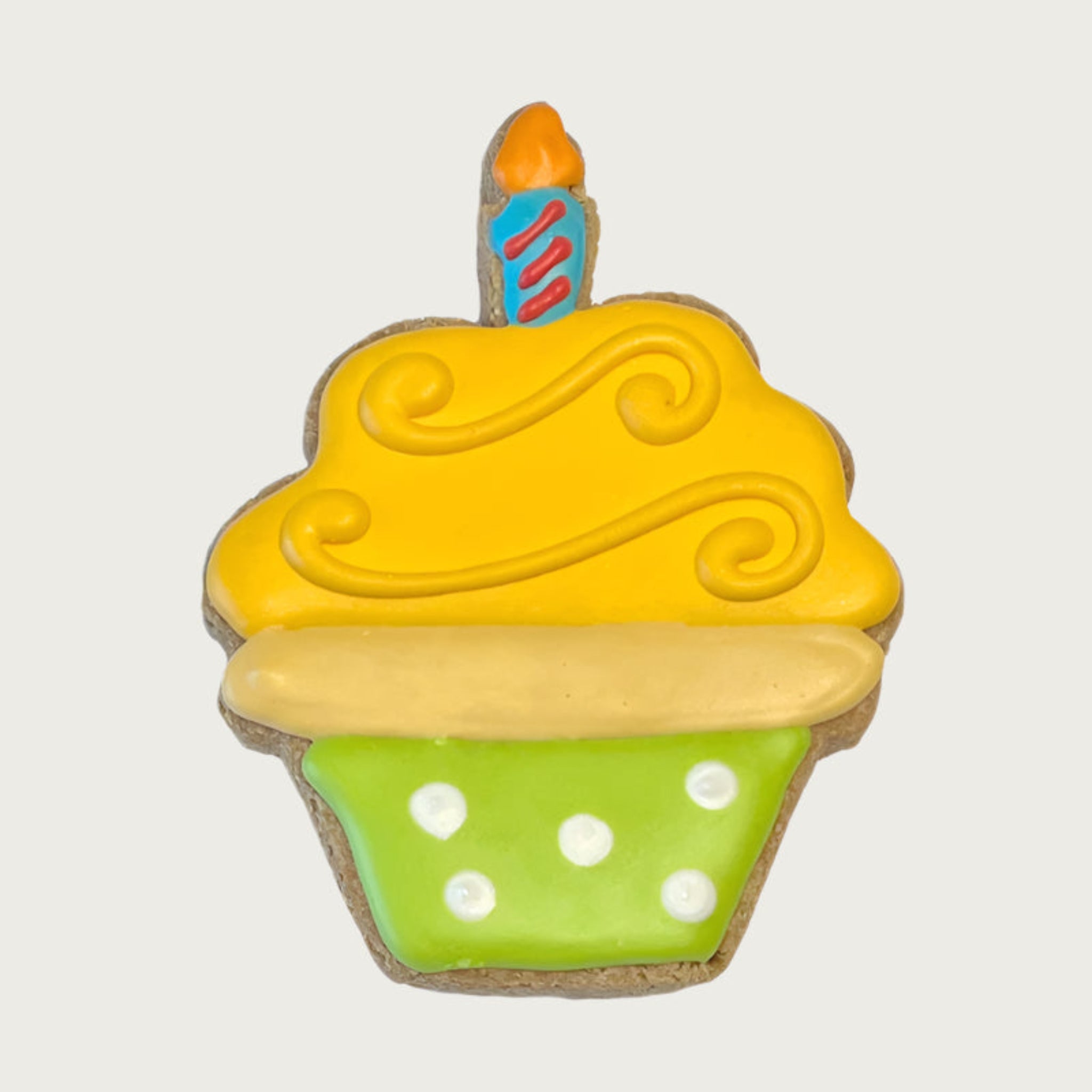 Dog cookie shaped like a birthday cupcake, with lime green base with white polka dots, yellow swirled "frosting", and blue & orange "candle".