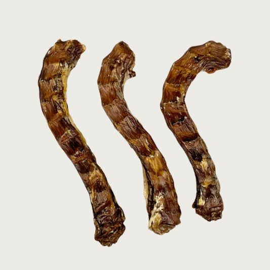 Three duck neck dog chews side by side to show size & shape variations. They are dark brown in color and have a slightly curved shape.