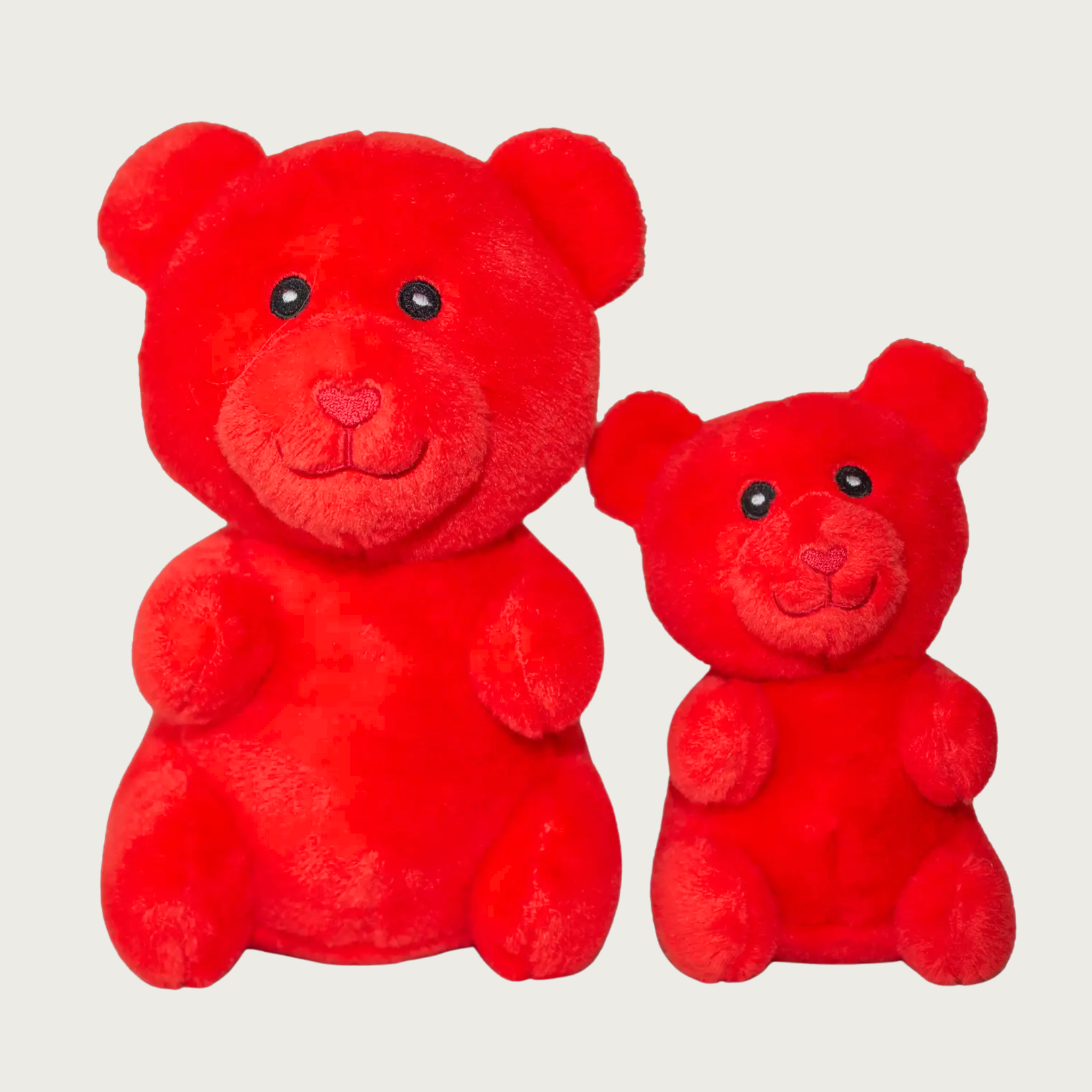 Two plush red gummy bear shaped dog toys, side by side to show size difference.
