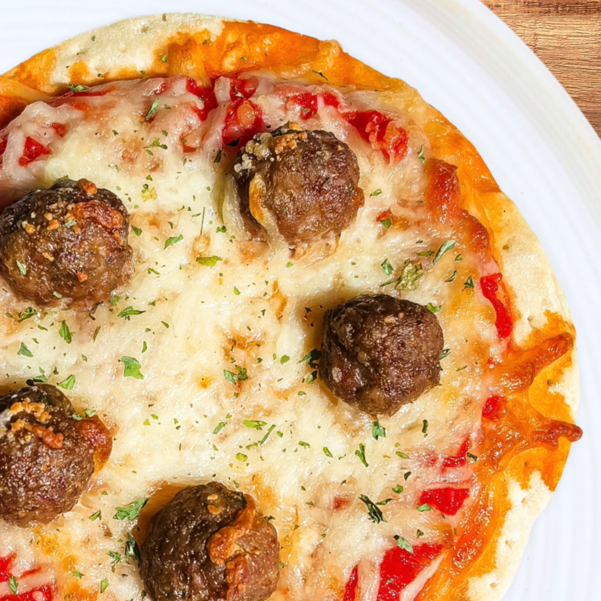 Pizza with meatballs on a white plate.