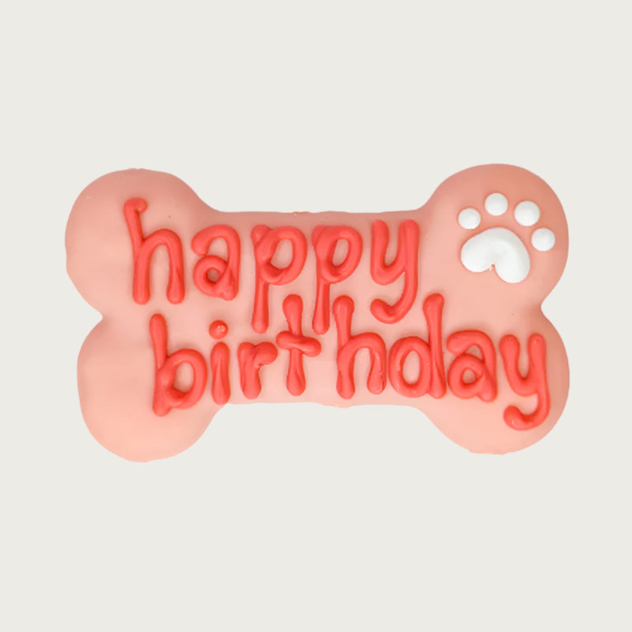 Pink bone-shaped dog cookie with 'happy birthday' text in darker pink, with white paw print accent.