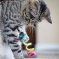 Load image into Gallery viewer, Tabby cat playing with the rainbow colored, spring cat toy. Toy has been outstretched, and kitty has it in his paw.