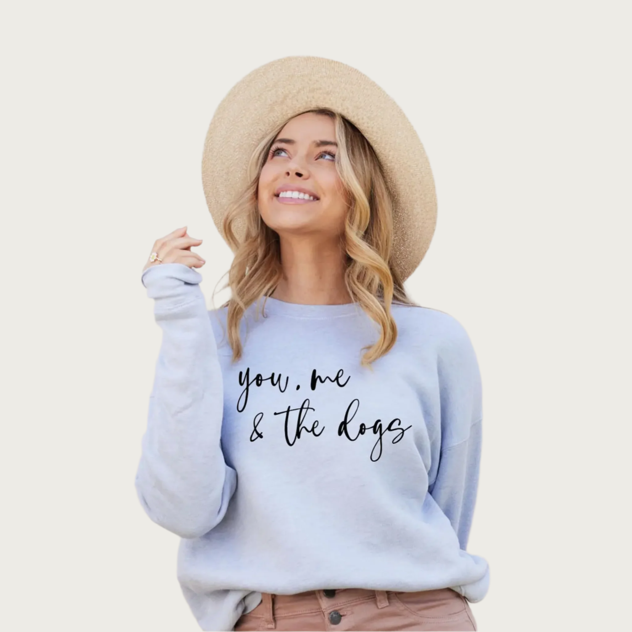Blonde model wearing a tan hat, wearing this sweatshirt. Color is very pale, light blue with black script text that reads "you, me & the dogs".