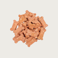 Load image into Gallery viewer, Closeup of a small pile of Strawberry Shortcake Bones dog treats. They are dog bone shaped, pinkish in color, with a grainy texture.