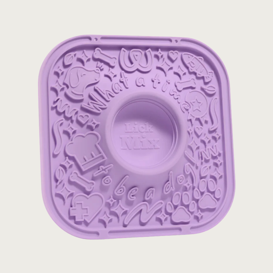 Lavender silicone lick mat for dogs, with raised, dog-themed graphics on the surface to hold spreads. In the center is a deep, round indentation to be used for mixing treat ingredients together.