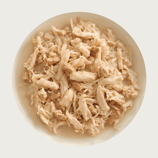 A bowl of Aujou by RAWZ Chicken Breast & Chicken Liver recipe, showing large chunks of chicken with smaller shreds and small pieces of chicken liver.