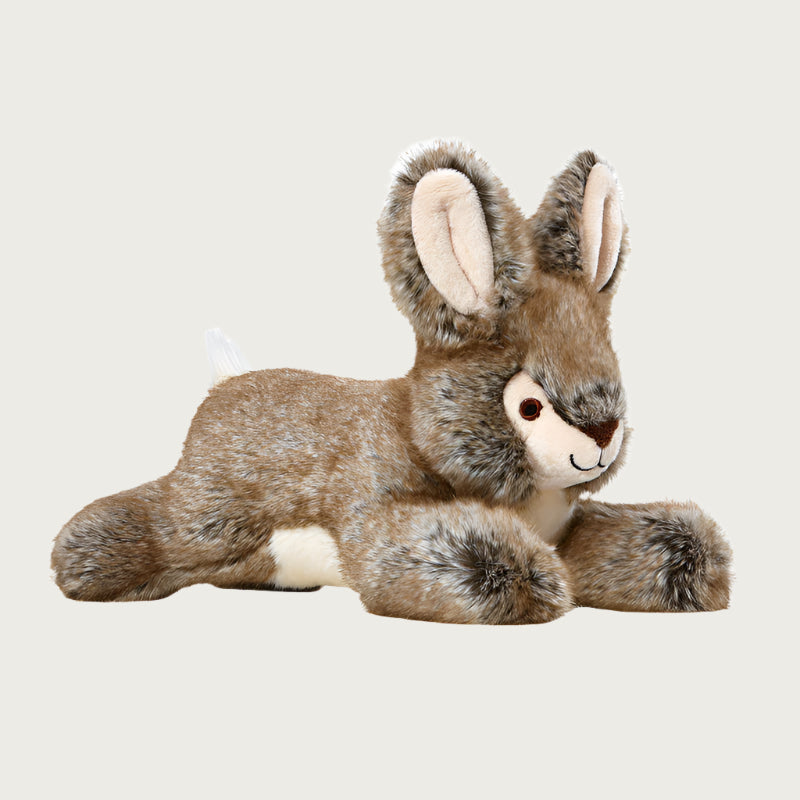 Plush Reese Rabbit dog toy from Fluff & Tuff. Its front and back legs are outstretched, and its body is a warm brownish gray, with cream tummy, tail, muzzle and inner ears.