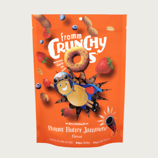 A 6 oz orange bag of Fromm Crunchy O's Multigrain Peanut Butter Jammers flavor dog treats. Mini photos of the round ring shaped treats, whole, unshelled peanuts, strawberries and blueberries are featured, along with an illustration of a flying peanut man being shot out of a cannon.