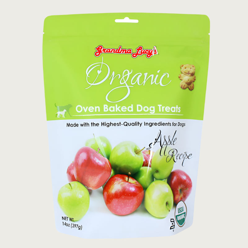 14 oz white & green apple colored bag of Grandma Lucy's Organic Oven Baked Dog Treats. Apple Recipe. Made with the highest-quality ingredients for dogs. Photo of a variety of apples is on the bottom half of the bag. A true to size image of the actual teddy bear shaped cookie treat, is near the brand name at top of bag. It's about 2" tall.
