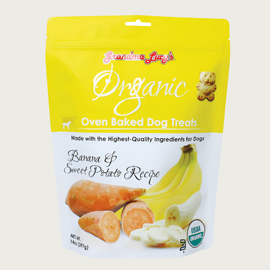 14 oz white & yellow colored bag of Grandma Lucy's Organic Oven Baked Dog Treats. Banana & sweet potato Recipe. Made with the highest-quality ingredients for dogs. Photo of a cut sweet potato and cut banana is on the bottom half of the bag. A true to size image of the actual teddy bear shaped cookie treat, is near the brand name at top of bag. It's about 2" tall.