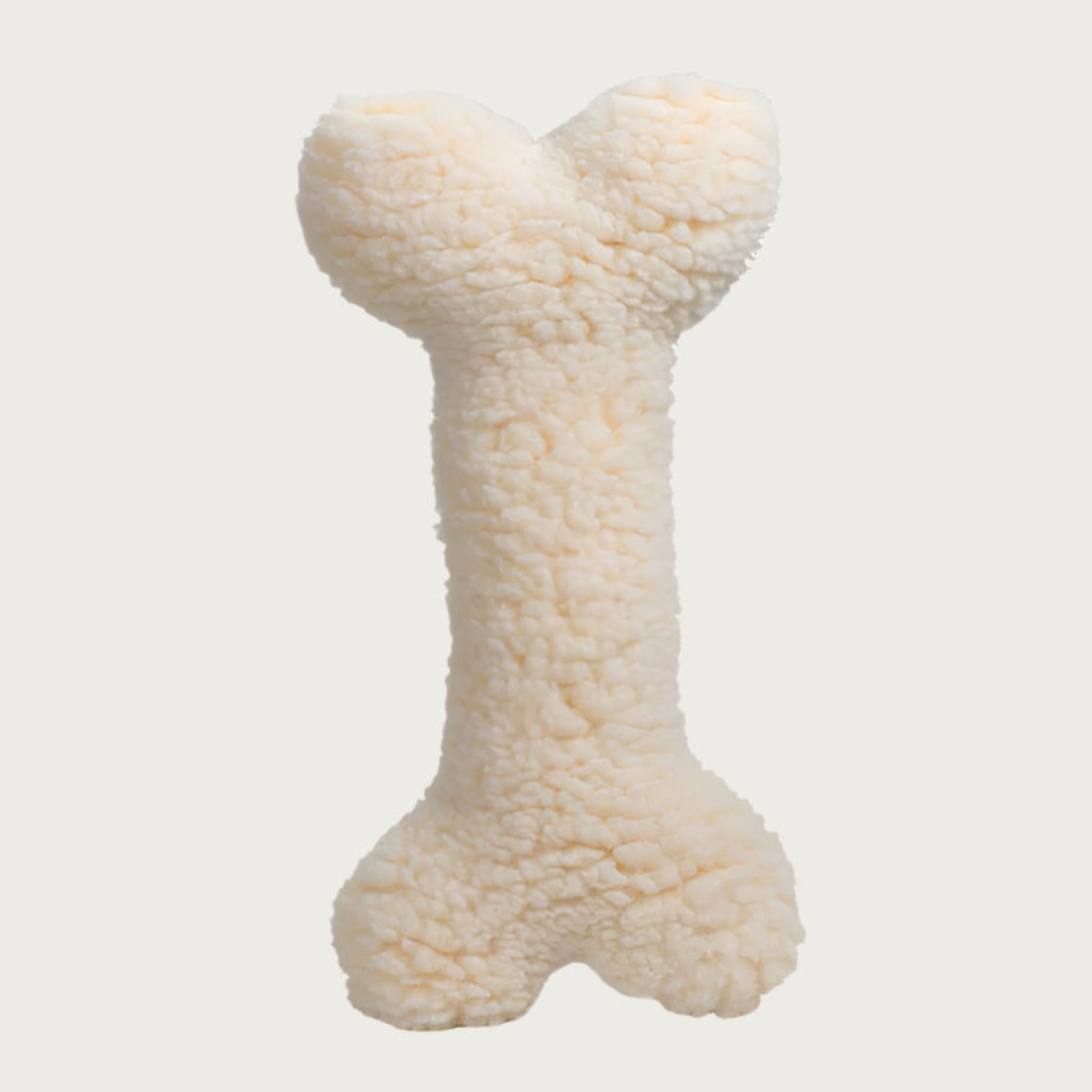Reverse side of the Tartan Tidings Bone dog toy. It is solid cream colored, faux lambswool.