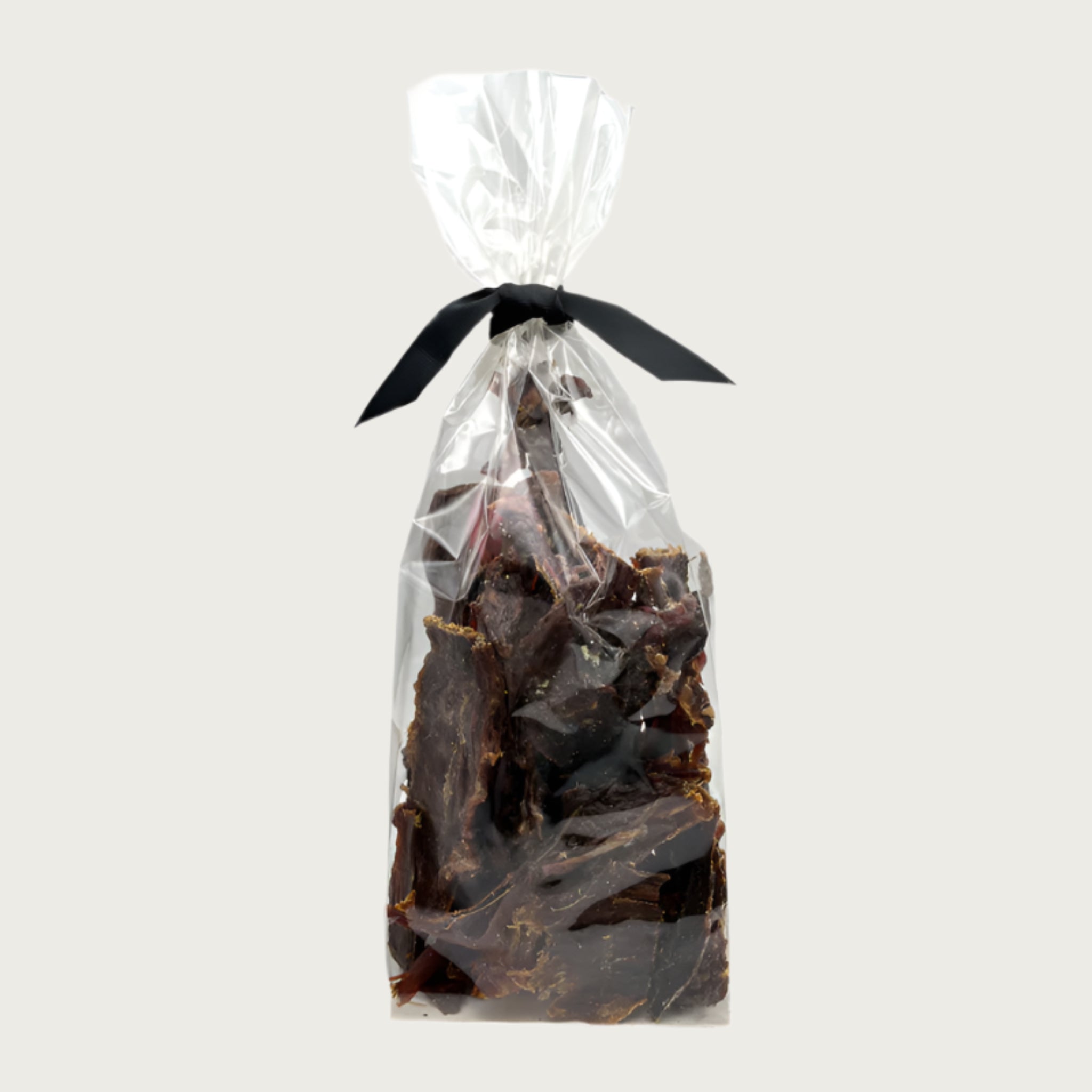 7 oz clear cellophane bag of Wet Nose exclusive Buffalo Jerky dog treats, tied with black ribbon. Product inside is brown, rectangular shaped strips.