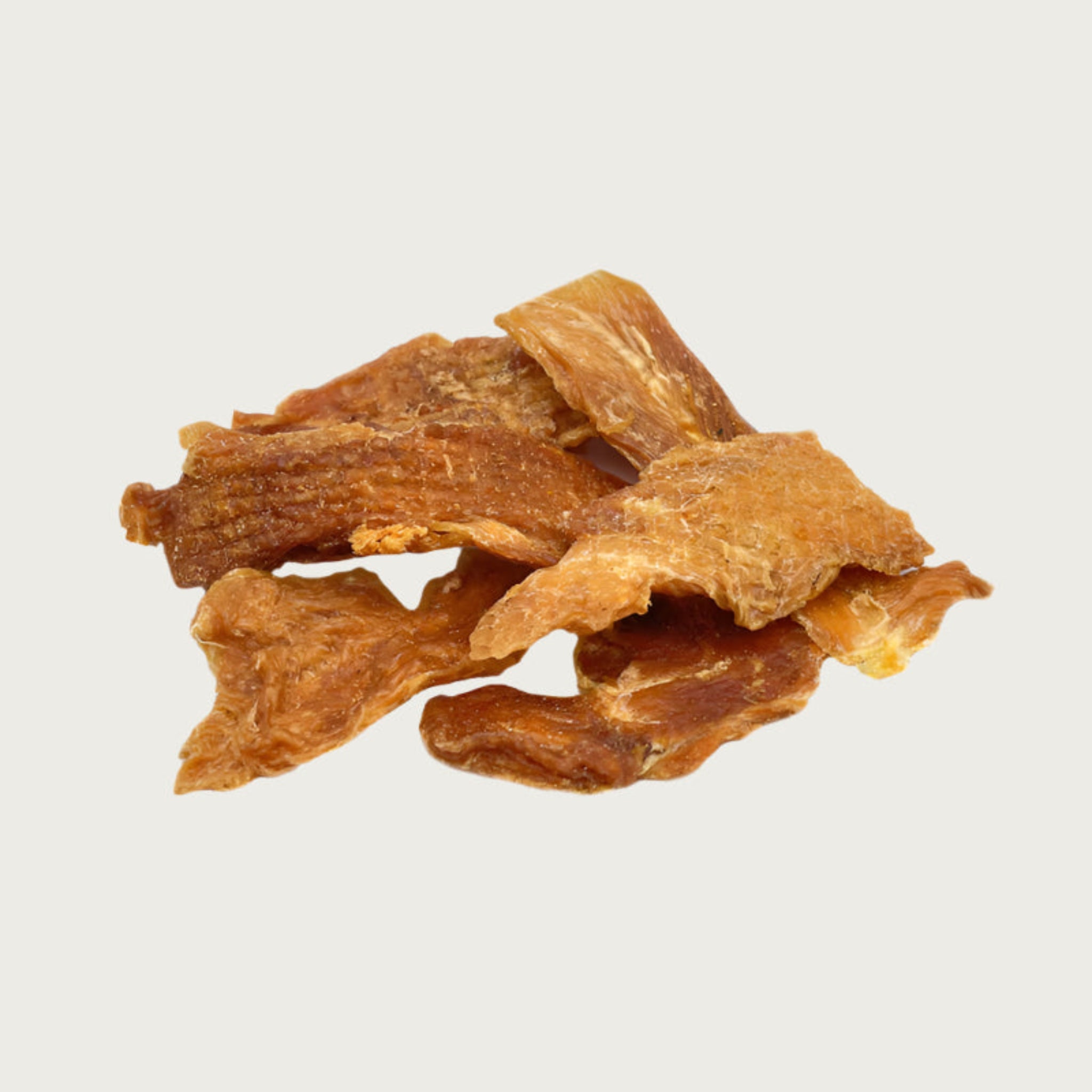 A close-up photo of a small pile of Wet Nose Chicken Strips dog treats. They are strips of chicken tenders, about 5"-6" long, and pale orangey-tan in color.