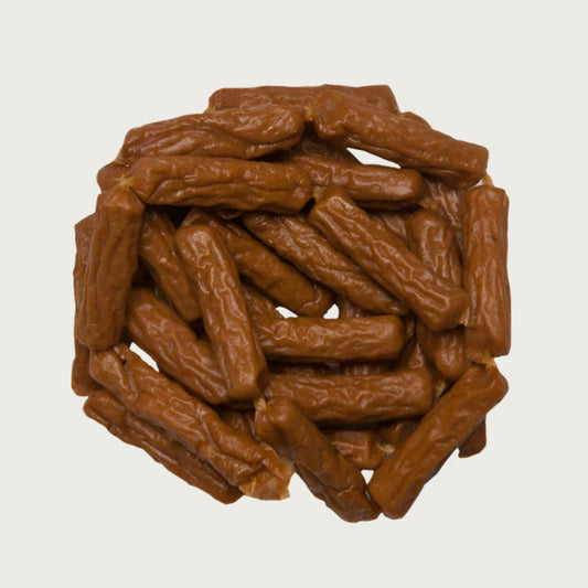 Close-up photo of a small stack of Wet Nose Duck Smokies dog treats. They are medium brown colored links, measuring about 2.5" long.