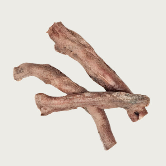 Three freeze-dried bully stick dog chews, stacked like sticks. Each has an uneven shape & width, and is light brown in color.