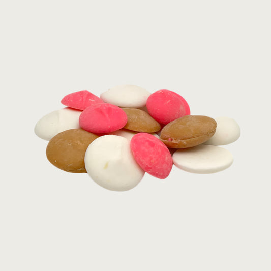 Closeup photo of a stack of Wet Nose Guilty Pleasures NeaPAWlitan flavored treats. They are tan, cream, and pink, disc-shaped, and measure about 1" wide.