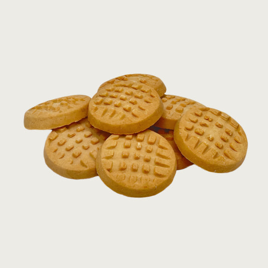 Closeup photo of a stack of Wet Nose Woof! Waffles peanut butter flavor dog treats. They are tan and round, and measure about 1.5" wide and 0.5" thick. Top of cookies are textured to look like homemade peanut butter cookies, with fork marks.