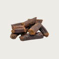 Load image into Gallery viewer, A close-up photo of a small stack of Wet Nose Misfit Duck Sticks dog treats. They are reddish brown in color about 2" long, with a slightly crumbly looking texture.