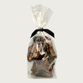 Load image into Gallery viewer, 4 oz clear cellophane bag of Wet Nose exclusive Moo Munch dog treats, tied with black ribbon. Product inside is visible; large and small square shaped, brown treats.