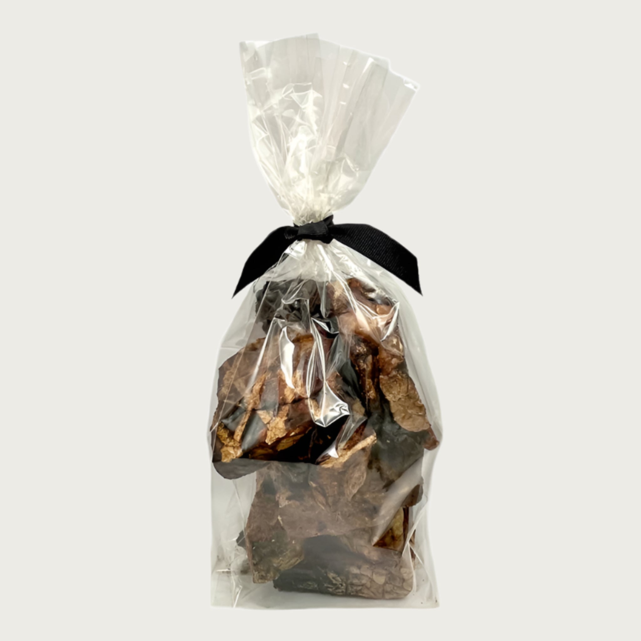 4 oz clear cellophane bag of Wet Nose exclusive Moo Munch dog treats, tied with black ribbon. Product inside is visible; large and small square shaped, brown treats.