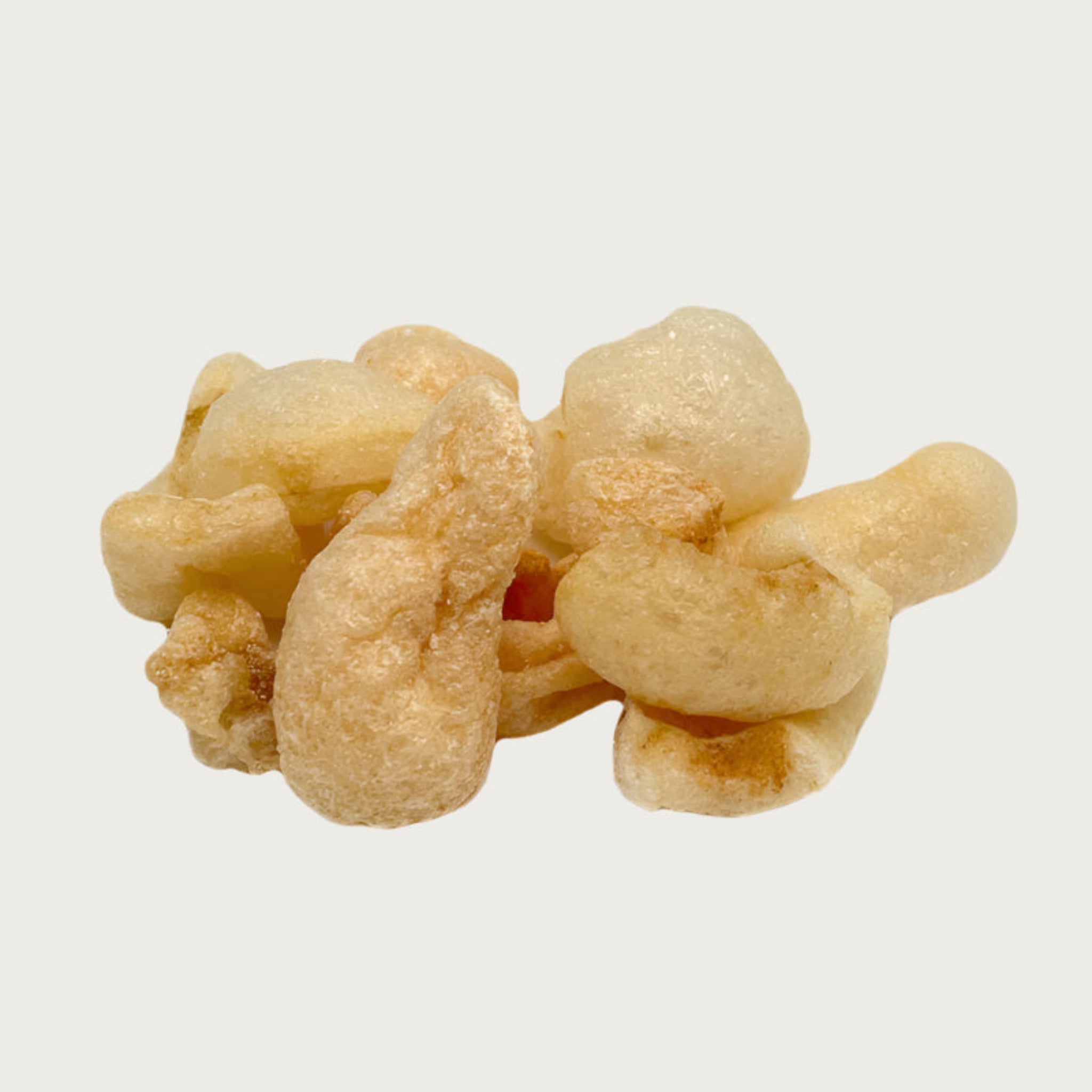 Close-up photo of a small pile of Wet Nose Moo Rinds dog treats. They are ivory colored, about 2"-3" long, and have a curved, uneven shape. They look airy, like the pork rinds that people would eat.