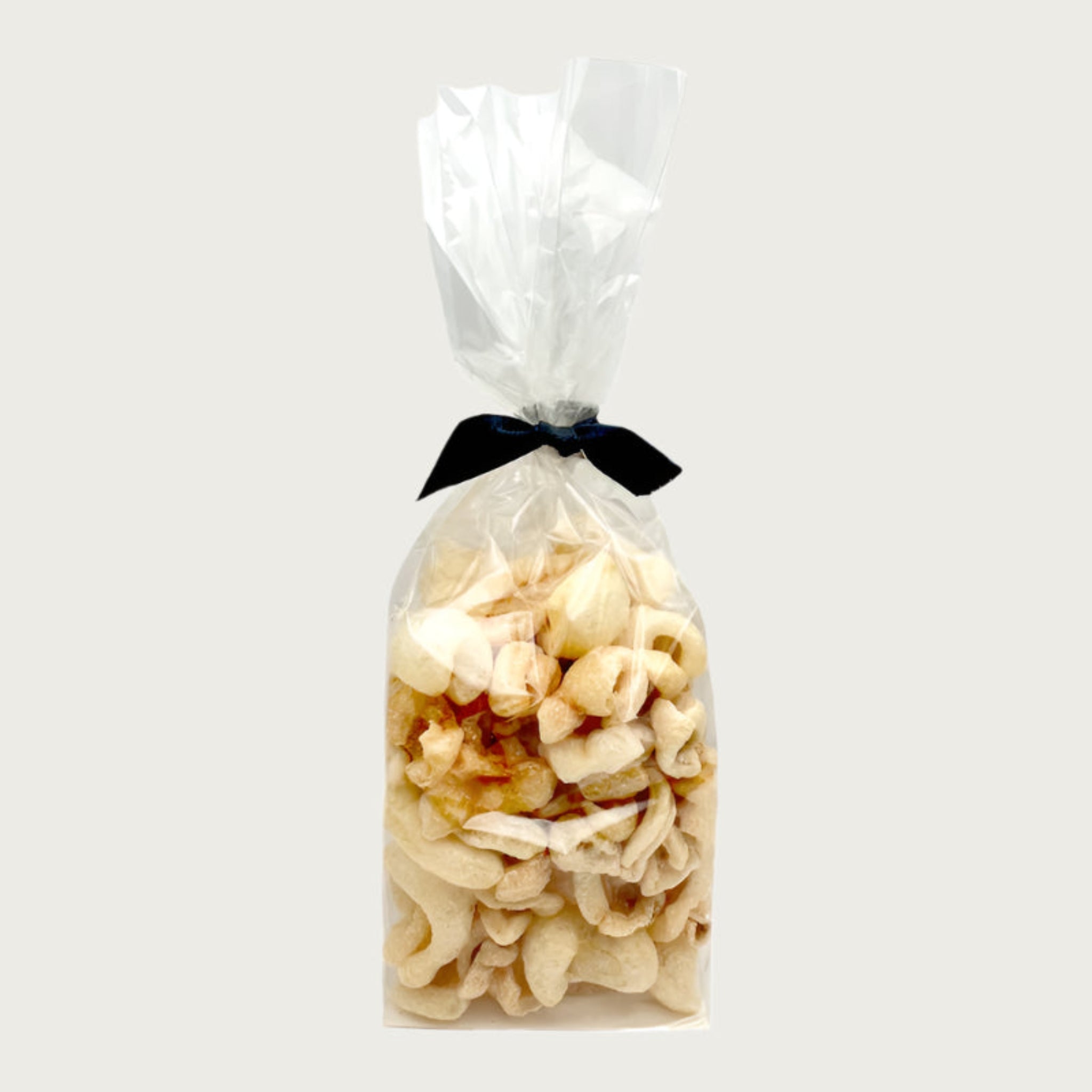 2 oz clear cellophane bag of Wet Nose exclusive Moo Rinds dog treats, tied with black ribbon. Treats inside are ivory colored, and look like thick, curled chips.