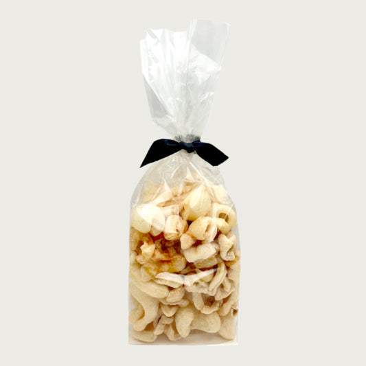 2 oz clear cellophane bag of Wet Nose exclusive Moo Rinds dog treats, tied with black ribbon. Treats inside are ivory colored, and look like thick, curled chips.