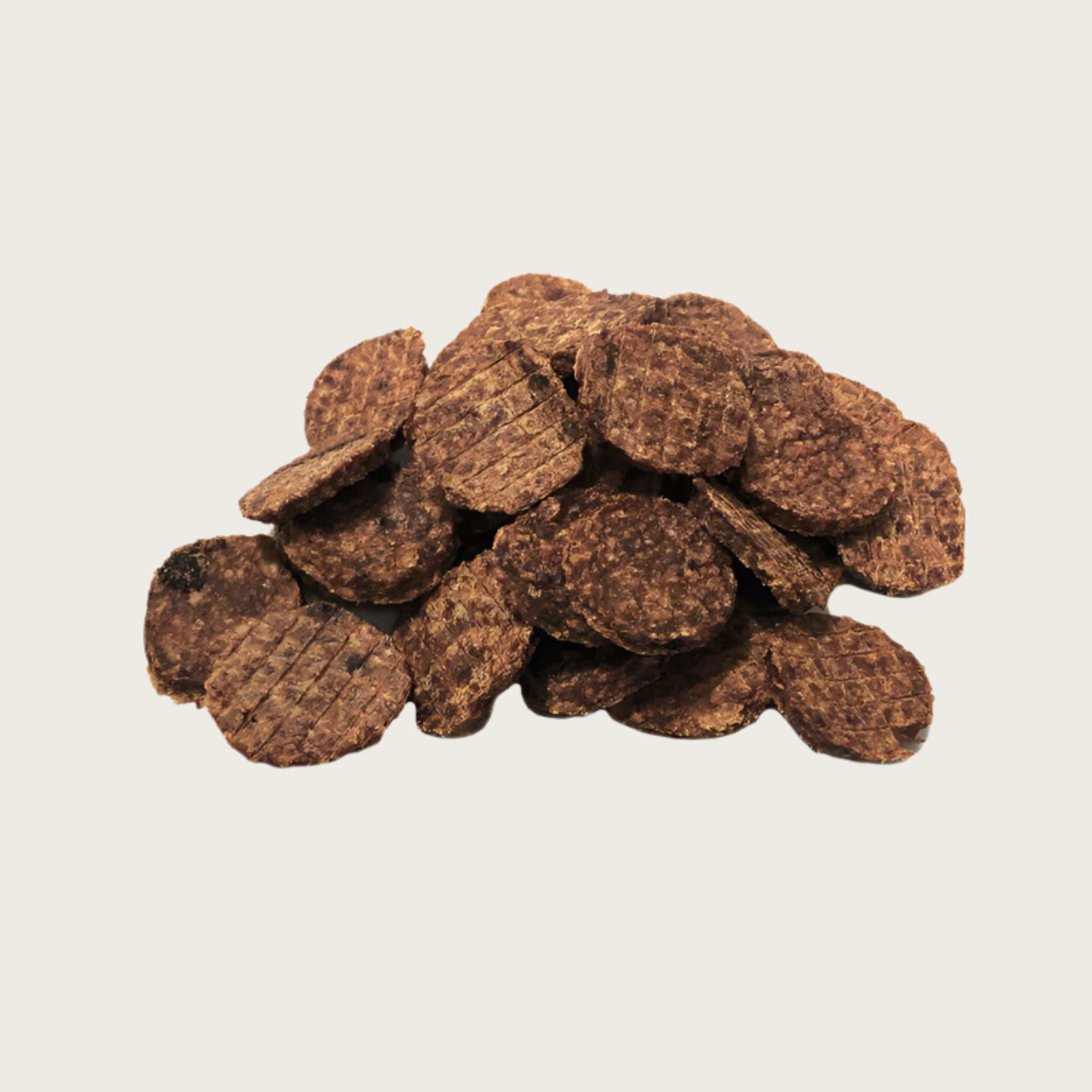A close-up photo of a small pile of Wet Nose Thumpers dog treats. They are brown, round discs, about 2" wide and 1/4" thick.